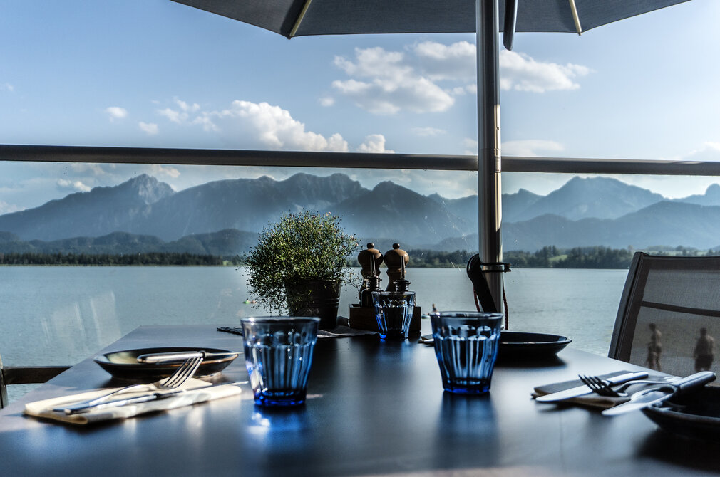 Restaurant table overlooking a lake and the Bavarian mountains