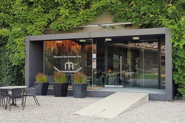 The glazed entrance of the Museum Starnberger See, framed by greenery