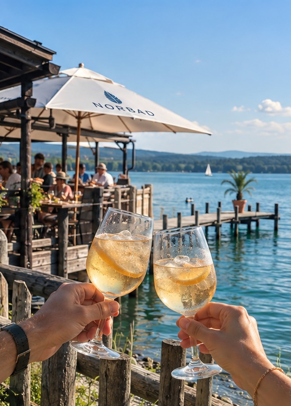 Two glasses raised for a toast on a lakeside terrace at Lake Starnberg